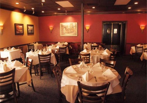 Dining room with white tablecloths tables and chairs inside the dining room at Amelia's