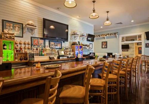 Interior of Gators Den Sports Grill with chairs in front of the bar and University of Florida decorations on the wall