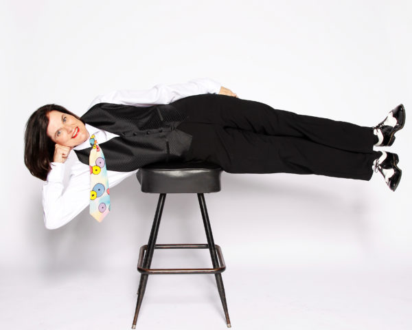 Paula Poundstone laying horizontal on a stool