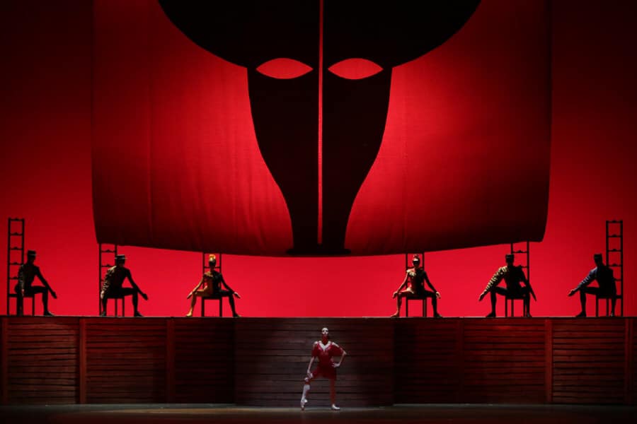 Dancers on stage with dramatic imagery of a bull fight