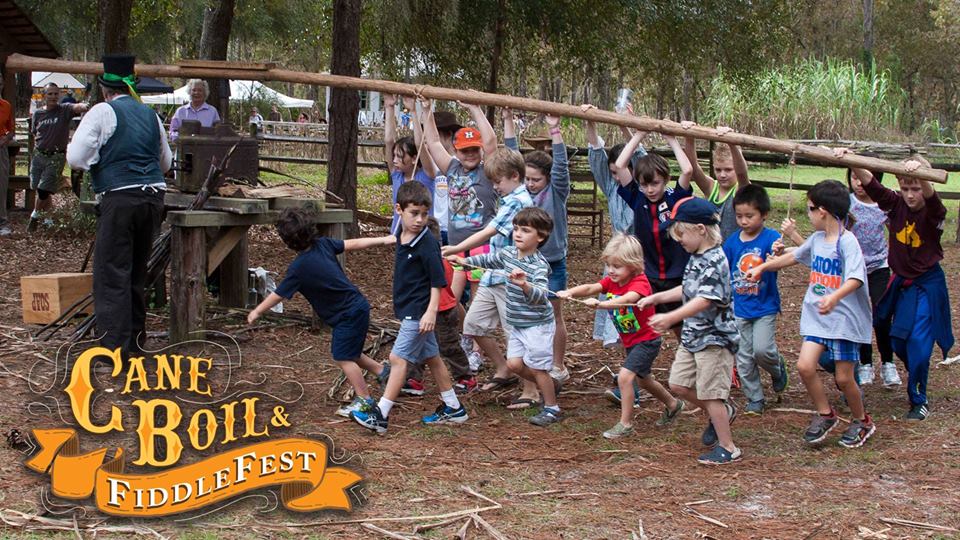 Kids operate the sugar cane press during Cane Boil and Fiddlefest
