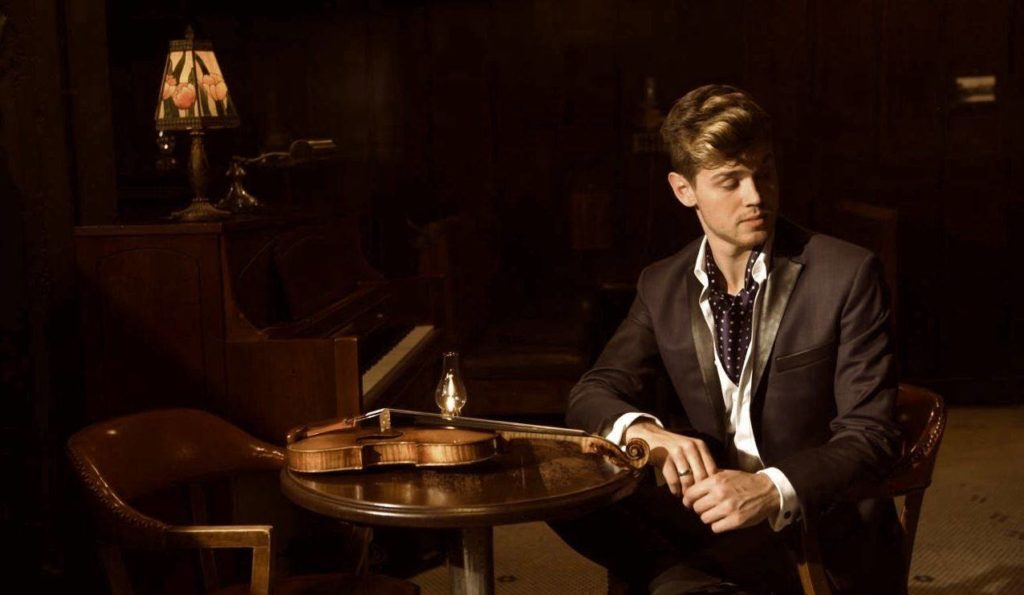Violinist Blake Pouliot sitting next to violin