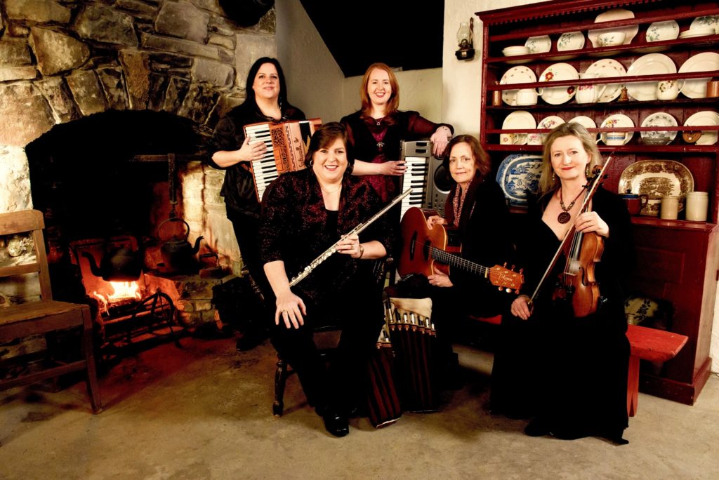Musicians with instruments by a fireplace for Cherish the Ladies A Celtic Christmas