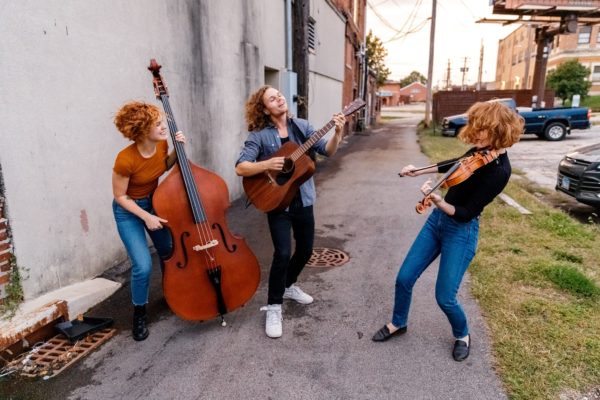 Band members of Good Morning Bedlam playing with instruments in an alley