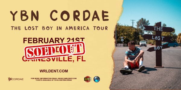 sitting on road with wayfinding signs reading "The Lost Boy"YBN Codae The Lost Boy In America Tour. Sold out