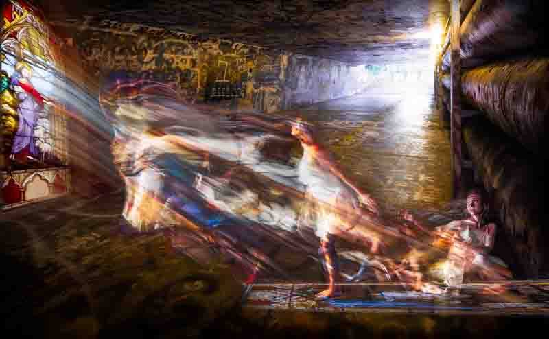 Abstract image of lighting shining through stained glass window with light shining on dancer
