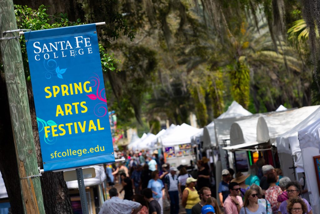 crowed gathered at the spring arts festival. tents line the streets. pole banner reads Spring Arts Festival