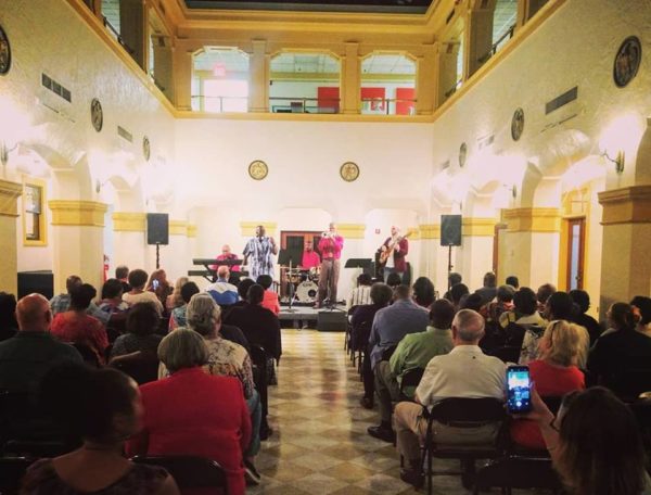 Crowd watching Lenard Perry on trumpet with jazz band on stage inside the Thomas Center.