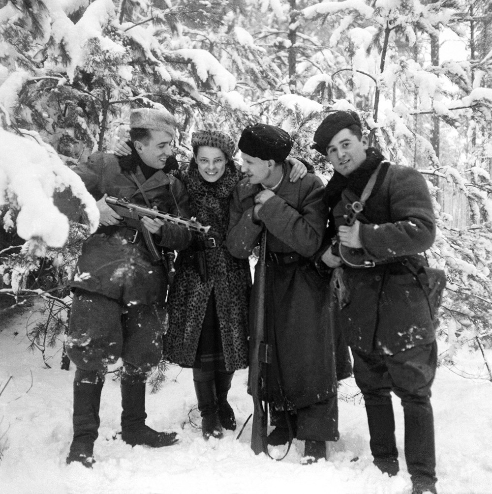 WWII image of girl in fur coat with soldiers in a snowy forest