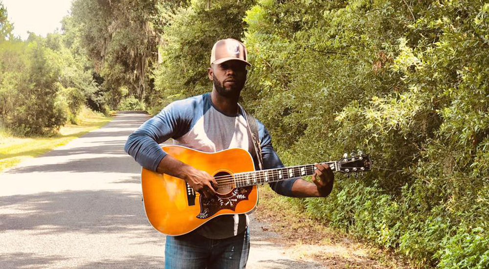 chris mcneil with guitar on a dirt road