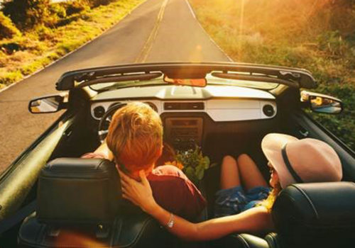 people enjoying a drive in a convertible down a scenic road