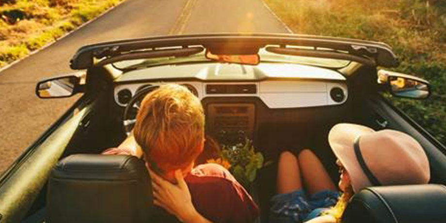 people enjoying a drive in a convertible down a scenic road