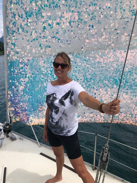Artist Sylvi Herrick standing on a sailboat
