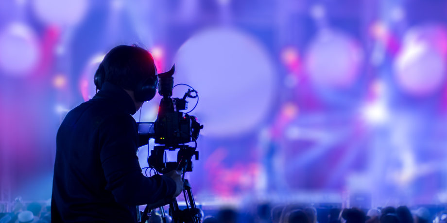 camera operator filming into lights of an event