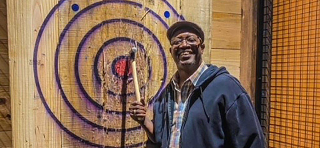 man next to axe throwing target