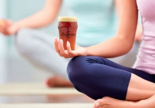 person doing yoga and holding beer