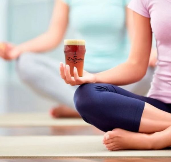 person doing yoga and holding beer