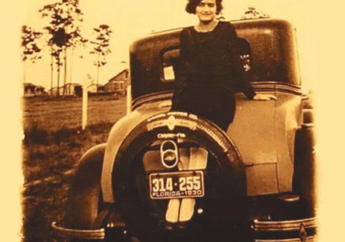 historic photo of woman leaning on car