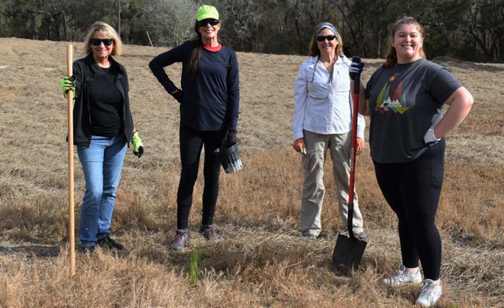 people holding shovels and planting trees