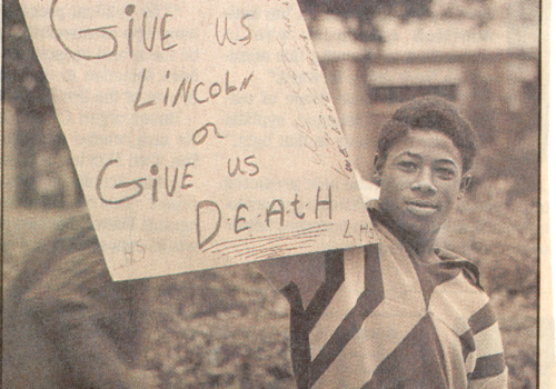 man holding up sign reading "give us lincoln or give us death"