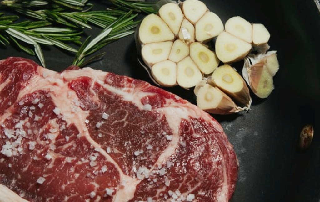 steak in pan with rosemary and garlic