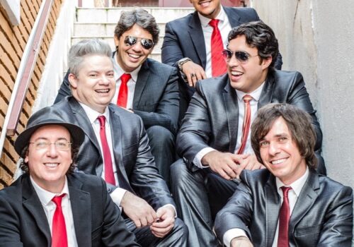 blue beatles band members in dark suits and red ties sitting on stair case