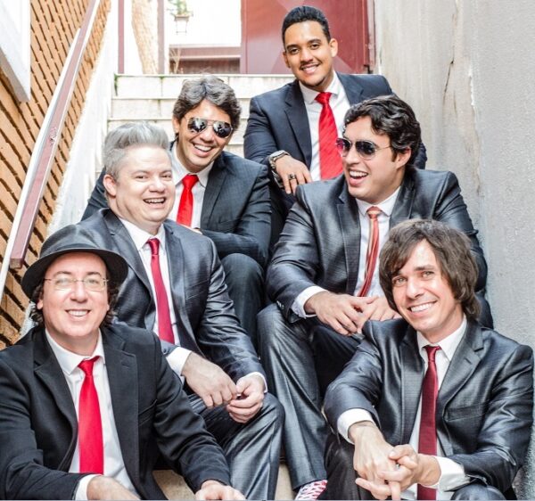 blue beatles band members in dark suits and red ties sitting on stair case