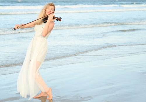 musician playing violin on beach