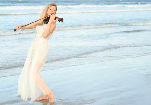 musician playing violin on beach