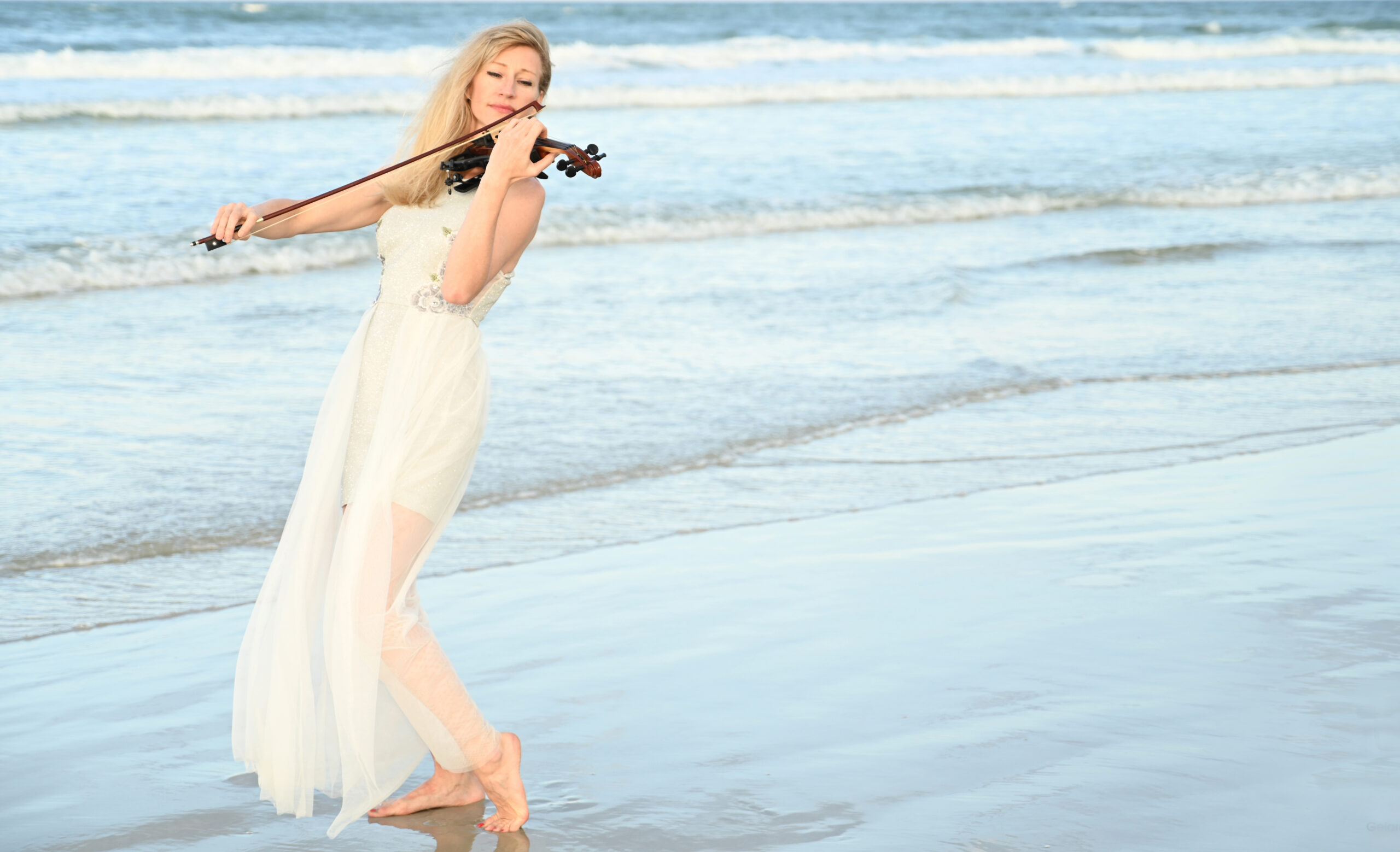 musician playing violin on beach
