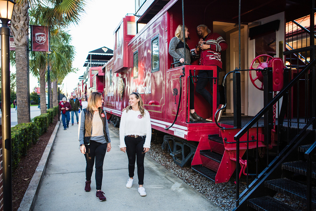 People walking and talking next to converted train cars in South Carolina