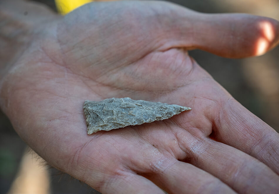 person holding an arrowhead in their hand