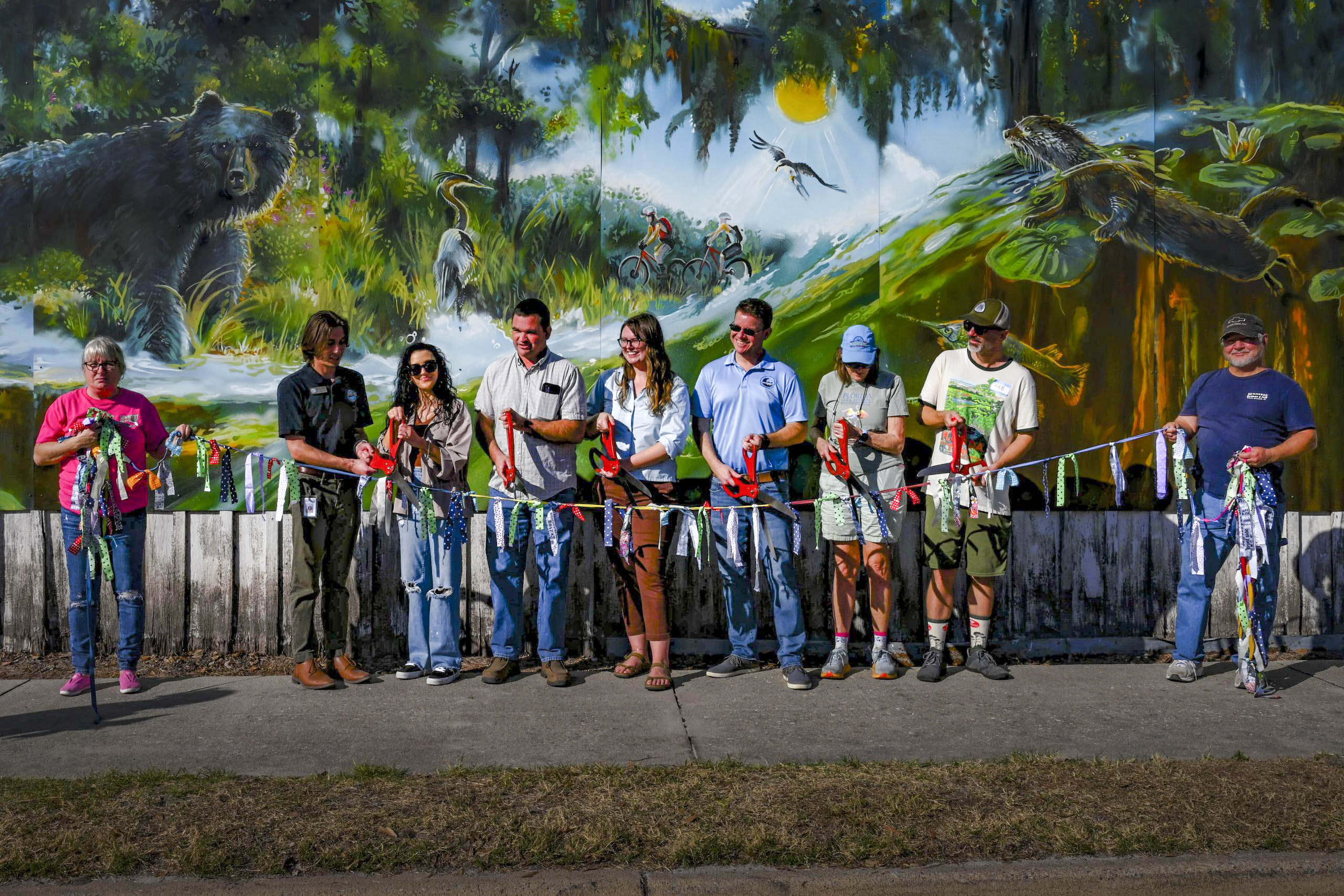 Community group in front of environmentally themed mural