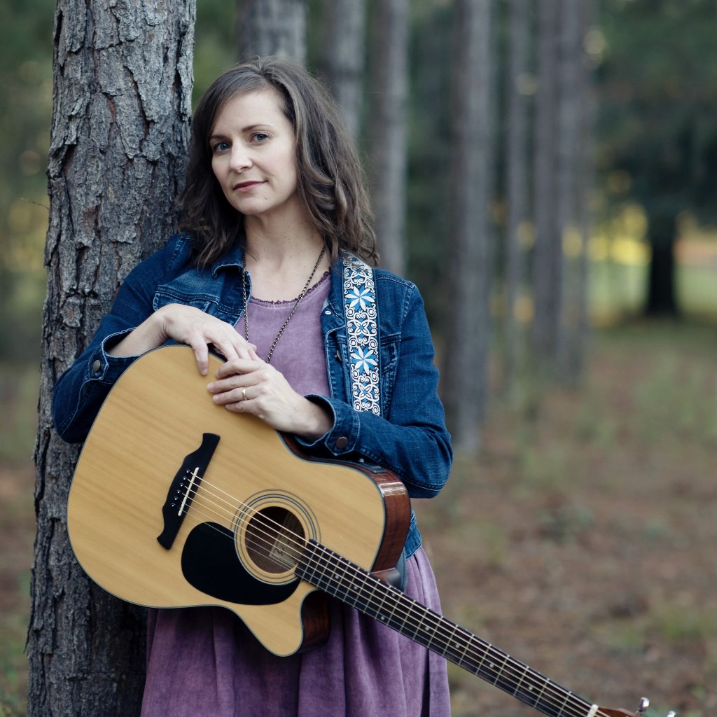 photo of rachel holding a guitar beside a tree