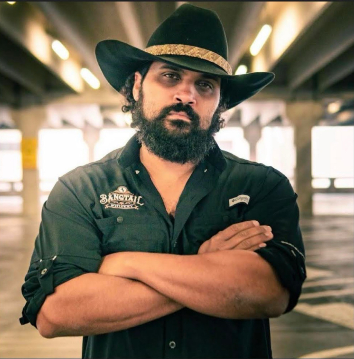 Photo of Brandon with his arms crossed in a cowboy hat